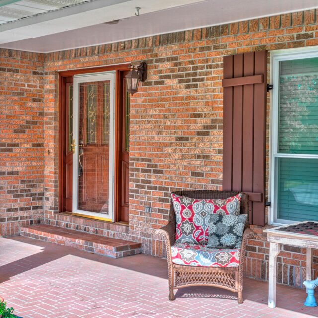 The font entrance to a red brick home with a storm door.